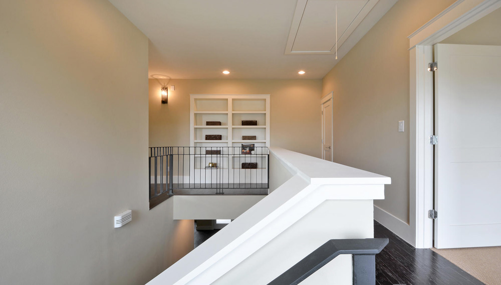 Second floor looking at stairs open to lower floor and built-in bookshelves.